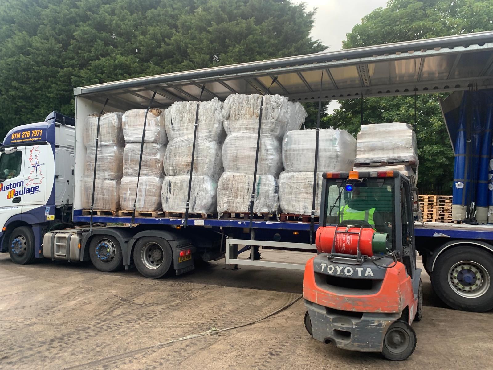 Forklift loading baled materials onto a collection vehicle