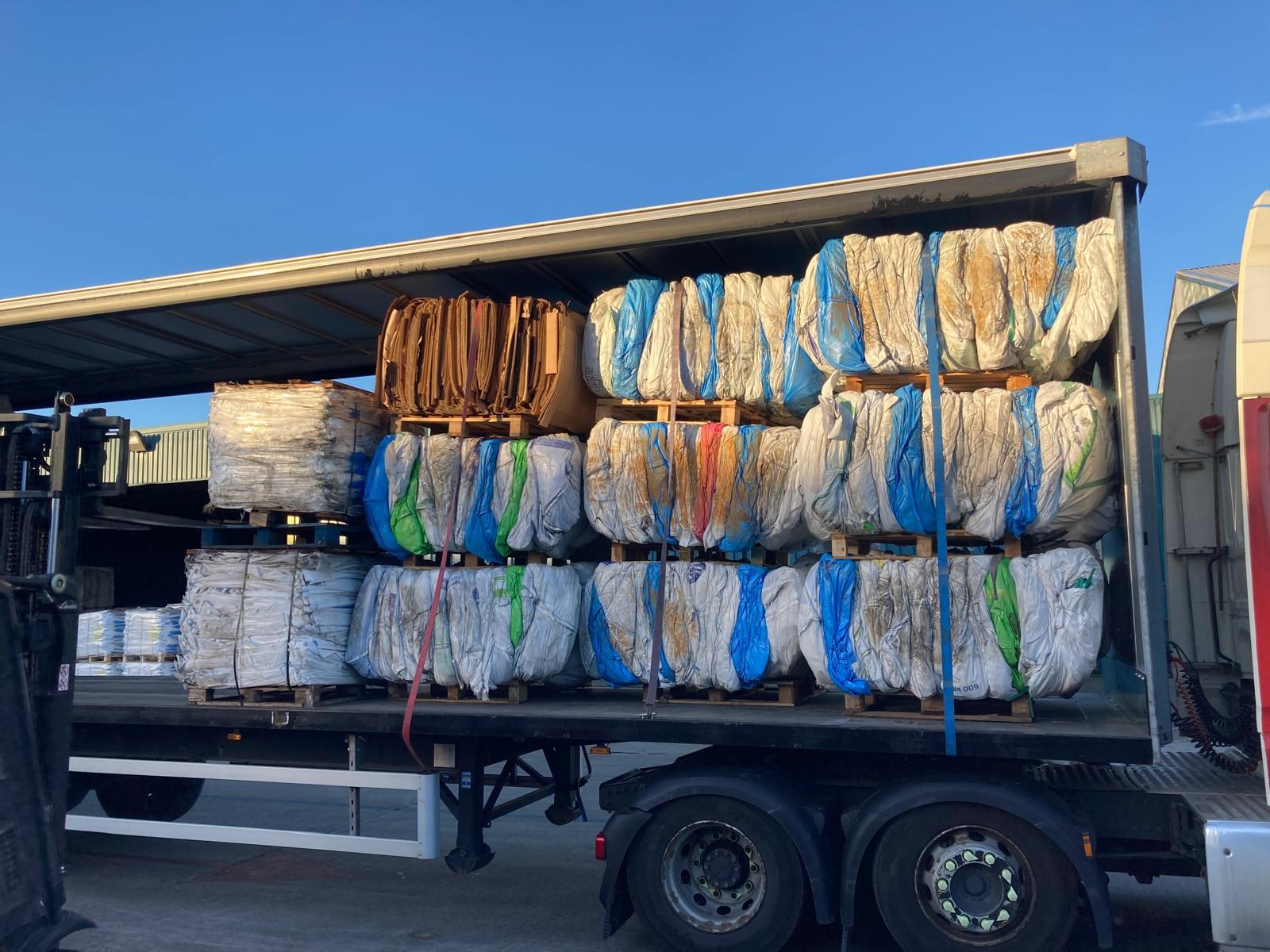 Coloured recyclable bales secured in a trailer
